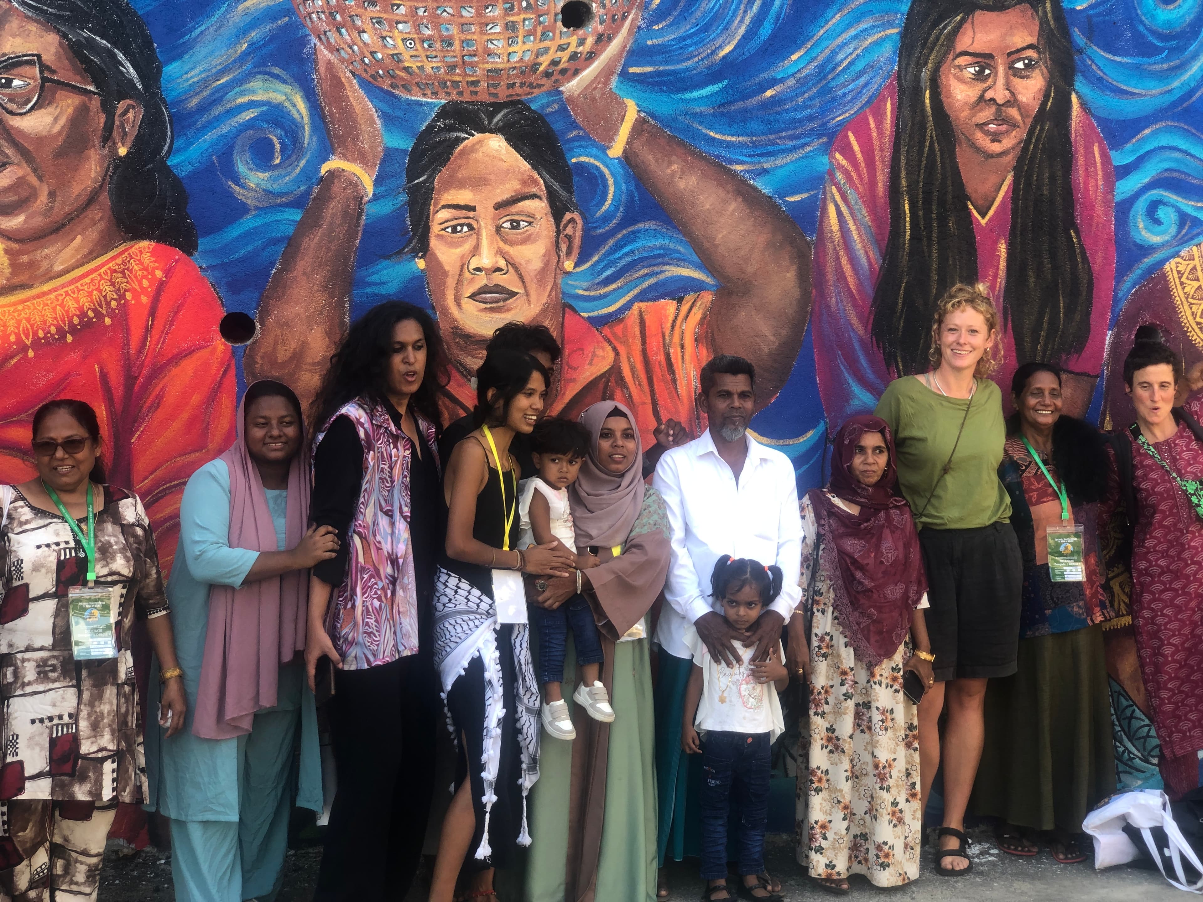 Nyeleni 2025 mural with delegates gathered in front of the artwork. - ACHFN, African & Caribbean Heritage Food Network